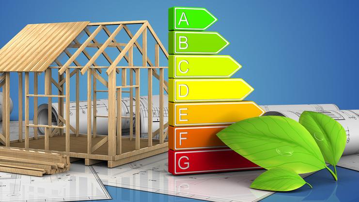 Modell eines Holzhauses neben einem Energieeffizienz-Ranking und Bauplänen auf einer blauen Hintergrundfläche.