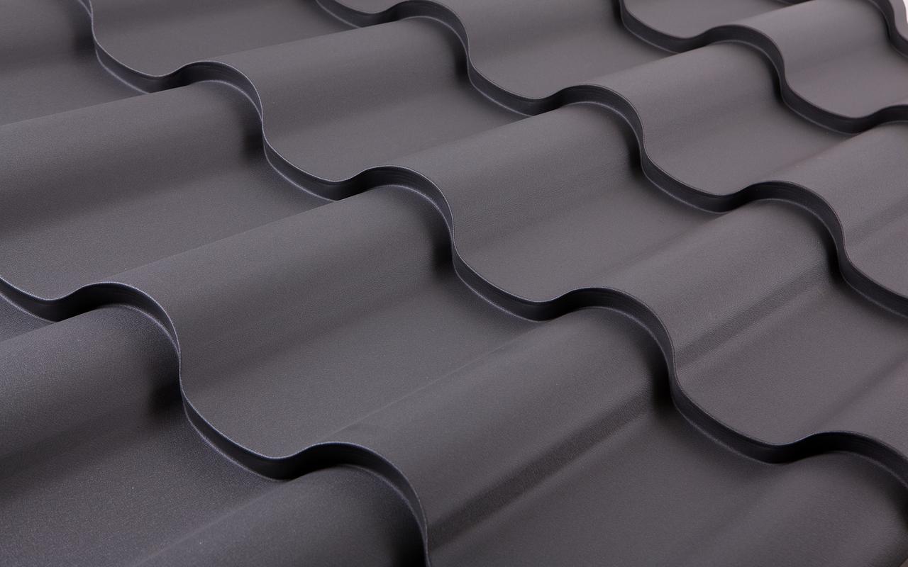 Nahaufnahme einer dunklen Wellblechdachplatte mit ausgeprägten, gewölbten Strukturen.